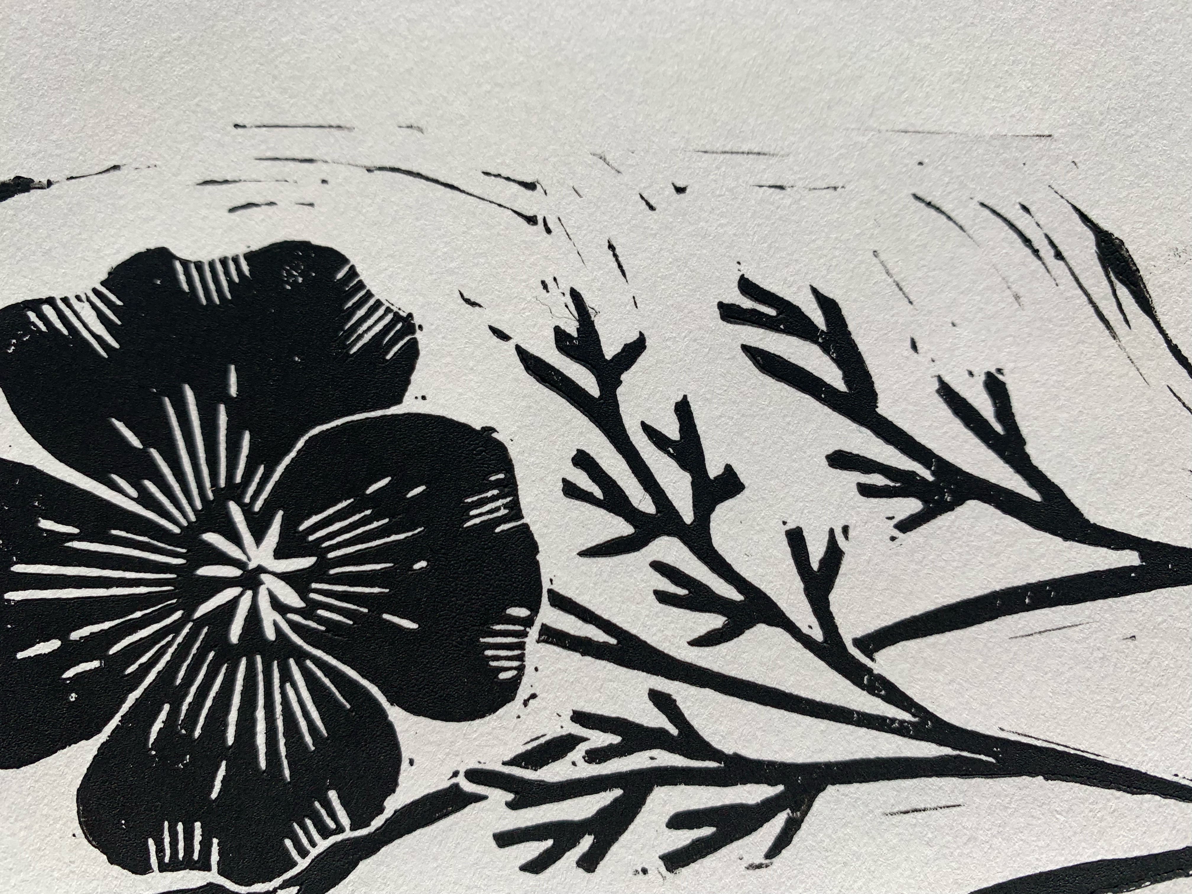 Detailed view of block print of California poppy on white paper in black ink.