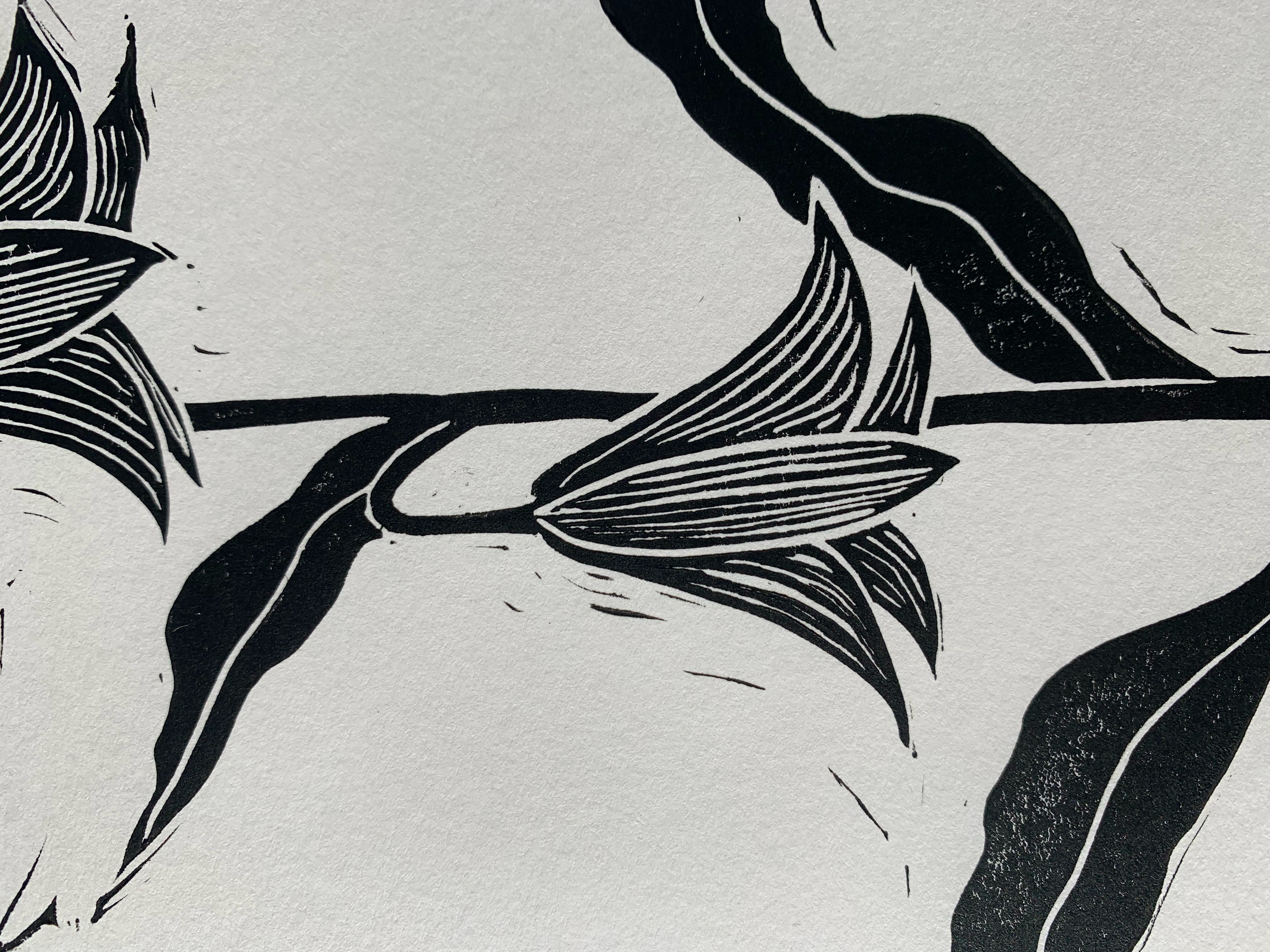Detailed view of block print of chocolate lily on white paper in black ink.